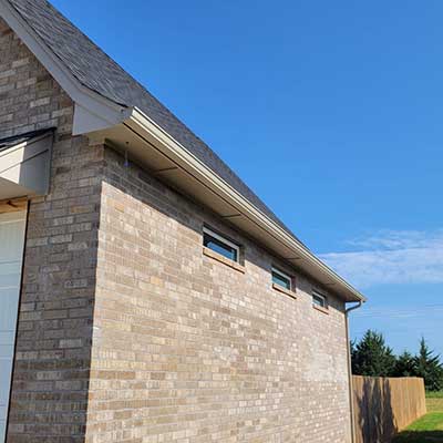 Side view of a home with newly installed beige, k-style gutters on the fascia