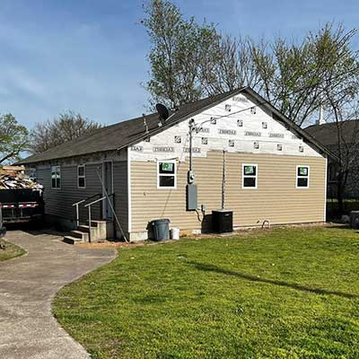 Small home getting new beige siding installed by Lira Roofing