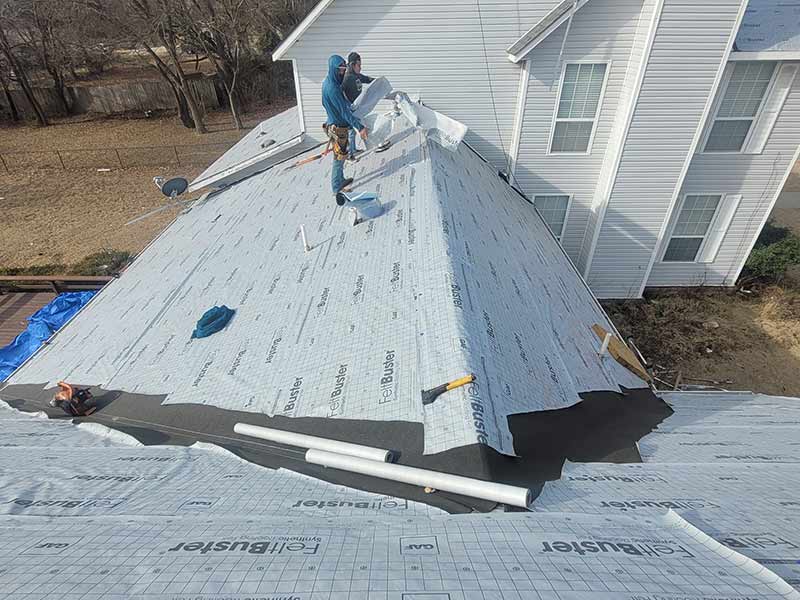 Two Lira Roofing workers getting a large residential roof ready for shingle installation