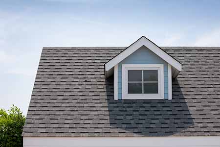Front view of a mid-class, light beige home with gray GAF shingles on its roof